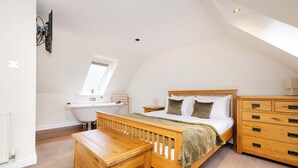 A bedroom with a wooden bed, a wooden dresser, a bench, a desk, and a window. - JOIVY Modern flats near Edinburgh Castle (Edinburgh)