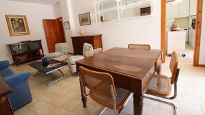 Un comedor con una mesa de madera, cuatro sillas, un sofá azul, un armario de madera y un espejo con iluminación.