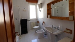Un baño con inodoro, bidé, lavabo y espejo.