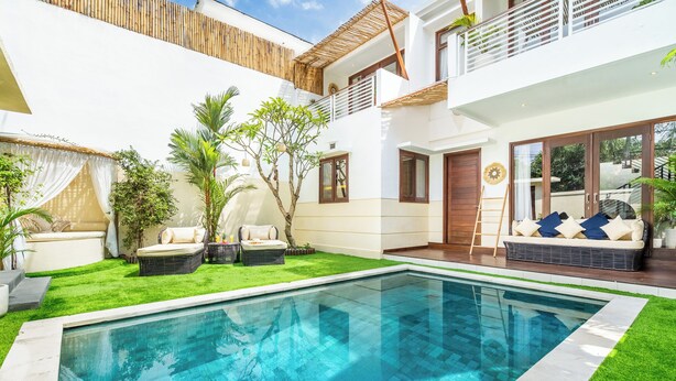 Ett modernt hus med en swimmingpool, utomhusmöbler och en balkong.