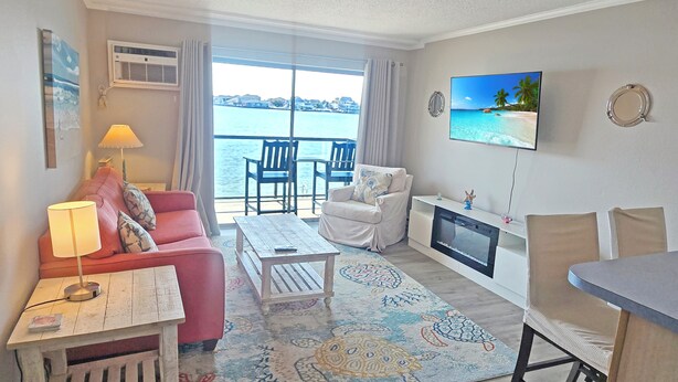 A living room with a sofa, chairs, a coffee table, a TV, and a fireplace.