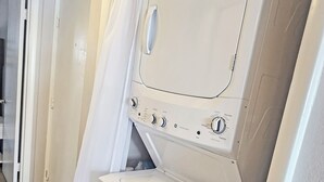 A white washer and dryer unit with control knobs and a transparent door.