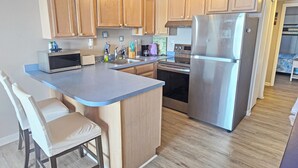 A modern kitchen with wooden cabinets, a stainless steel refrigerator, a microwave, and a built-in oven.