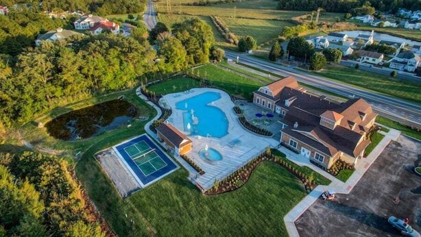 Luchtbeeld van een woongebied met huizen, een tennisbaan en een zwembad.