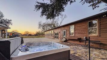 A wooden cabin with a hot tub and a covered seating area.