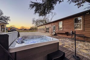 A wooden cabin with a hot tub and a covered seating area.