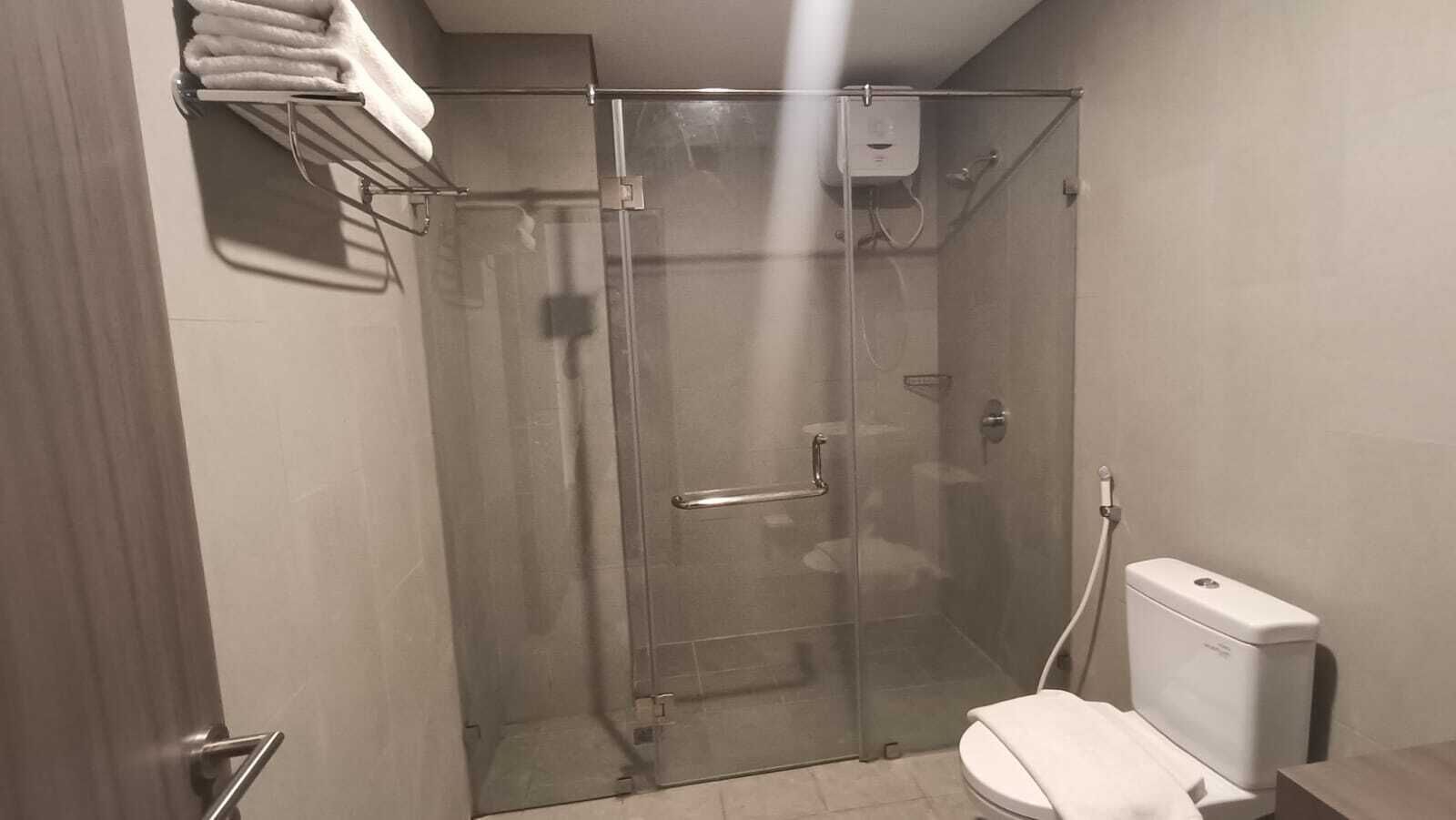 A shower with a glass door, a toilet, and a towel rack with towels.
