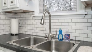 Keittiössä on kaksi ruostumattomasta teräksestä valmistettua pesuallasta, paperipyyhepidike ja ikkuna, jossa on sälekaihtimet.