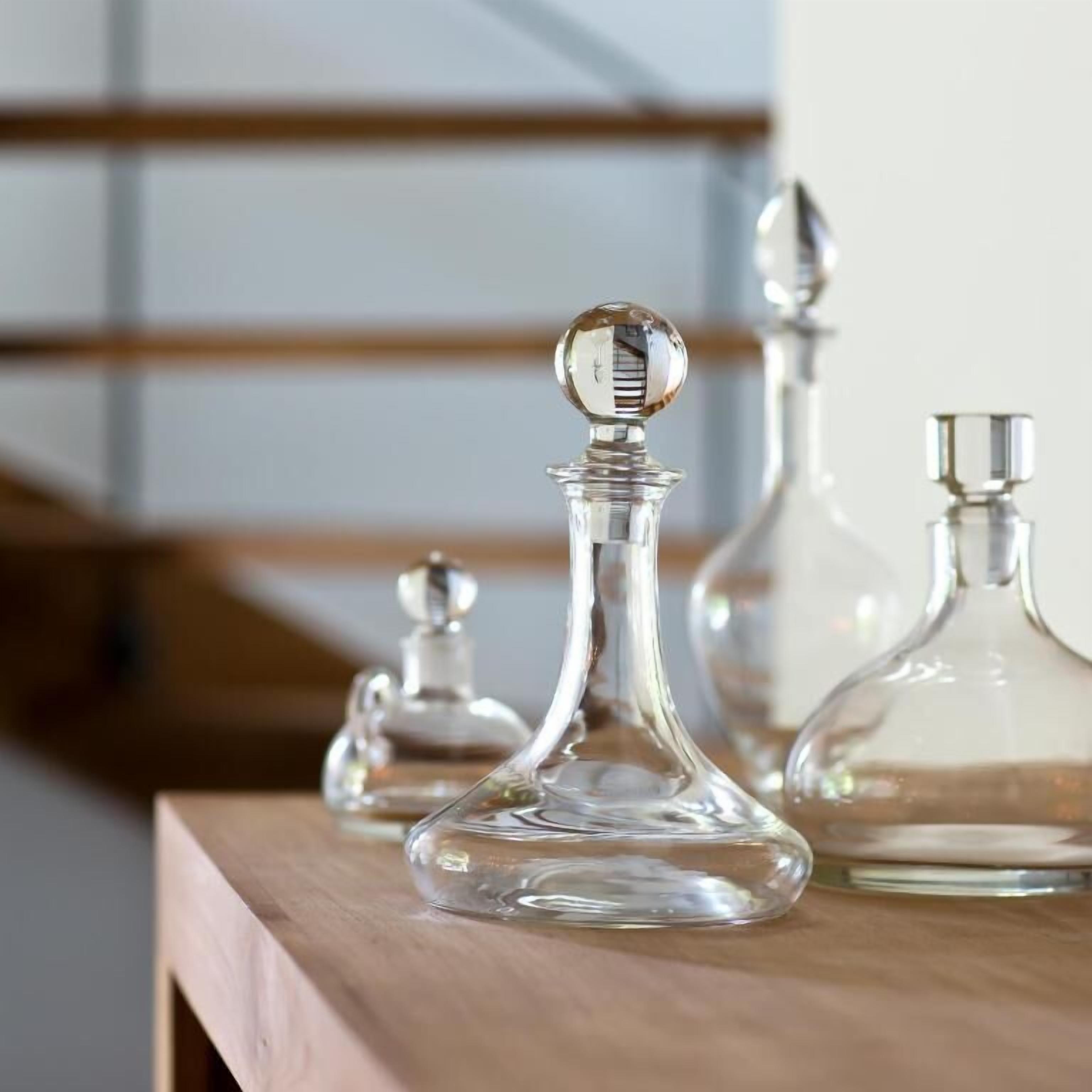 Een aantal glazen karafjes op een houten ondergrond.