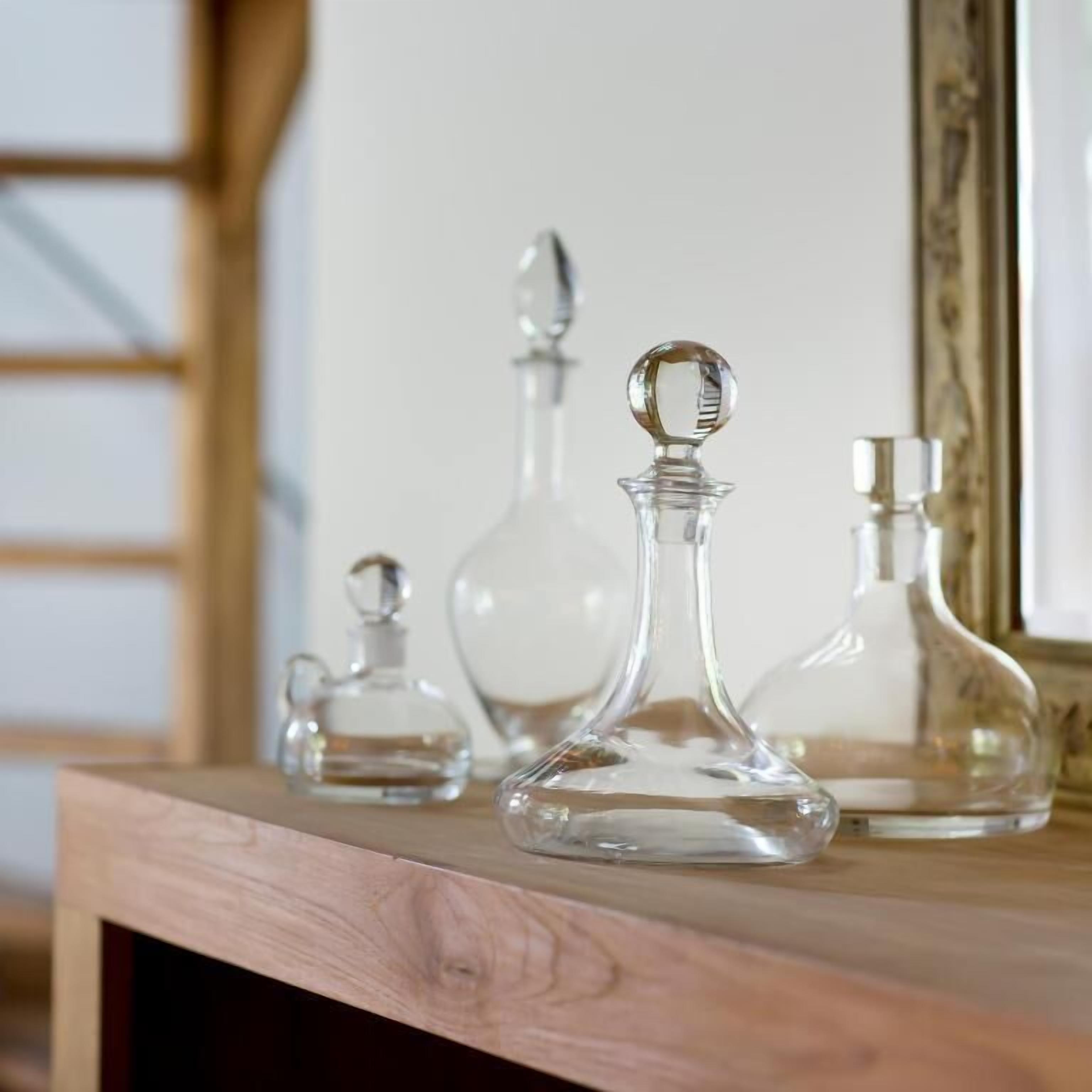 Tres botellas de cristal sobre una estantería de madera.