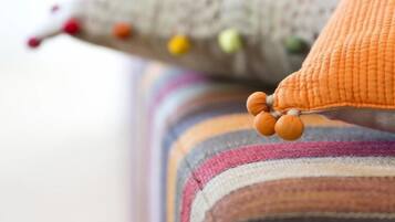 A close-up of a colorful, striped cushion with a textured fabric and a small, round, orange accent.