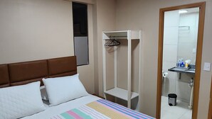 Een slaapkamer met een bed, een kledingkast en een badkamer, zichtbaar door een open deur.