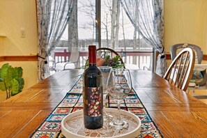 Una mesa de comedor con una botella de vino, dos copas y un atril decorativo.