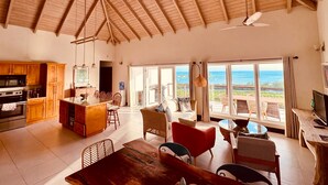 Un'ampia zona giorno con cucina, sala da pranzo e grandi finestre che offrono vista sull'oceano.