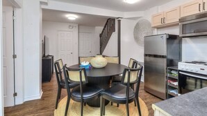 A compact kitchen with a round dining table, black chairs, a refrigerator, and a stove. - Fox Hotel Palais Des Congres (Montréal)