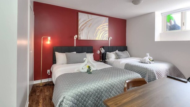 A hotel room with two beds, a wooden table, a painting on the wall, and a window with a view. - Fox Hotel Palais Des Congres (Montréal)