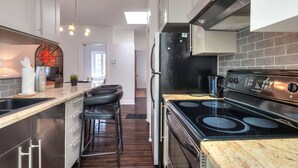 Una cocina moderna con estufa negra, electrodomésticos de acero inoxidable y encimera de mármol.