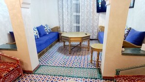 Una sala de estar con un sofá azul, una mesa de madera y un suelo estampado.