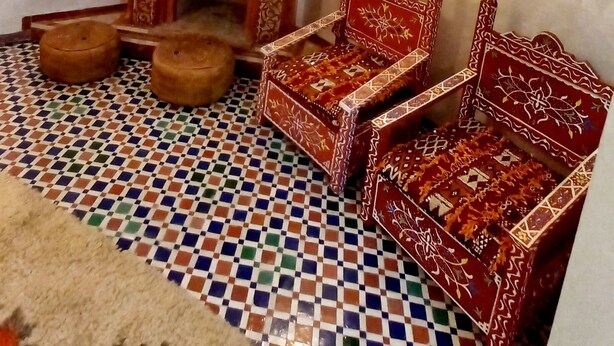 Una habitación tradicional con piso estampado, muebles ornamentados y una chimenea decorativa.