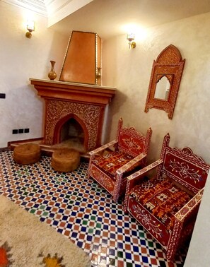 Habitació tradicional amb terra estampada, mobles ornamentals i una llar de foc decorativa.
