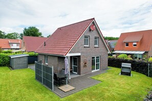 Ein zweistöckiges Haus mit rotem Ziegeldach, Backsteinfassade und einer kleinen angebauten Garage.