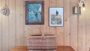 A wooden wall with two framed pictures, a woven basket, and a wall-mounted light fixture. - The cosy refuge (Chamonix-Mont-Blanc)