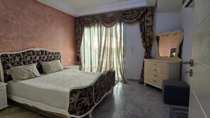 A bedroom with a bed, a dresser, a mirror, and a wardrobe.