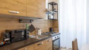 A modern kitchen with wooden cabinets, a built-in stove, a coffee machine, and a hanging rack. - Vatican Domvs, 250 meters from the Vatican Museums (Roma)
