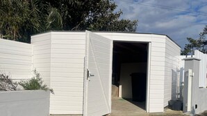 Un edificio blanco de un piso con un amplio acceso abierto.