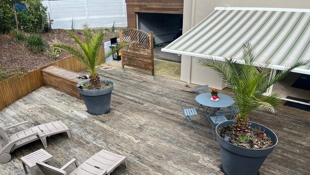 Un patio al aire libre con sillones de descanso, una mesita y plantas en macetas.