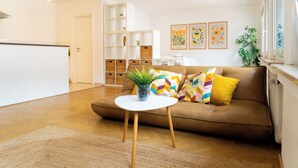 A living room with a brown sofa, a white coffee table, and a potted plant. - Cozy apartment+kitchen+Netflix (Essen)