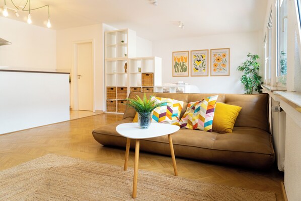 A living room with a brown sofa, a white coffee table, and a potted plant.