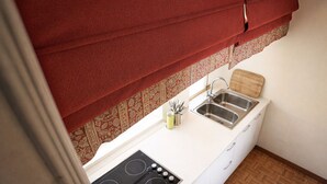 A compact kitchen with a stove, two sinks, and a wooden cutting board. - dHomes -Apartments Rooms- Galleria Gold  (Milan)