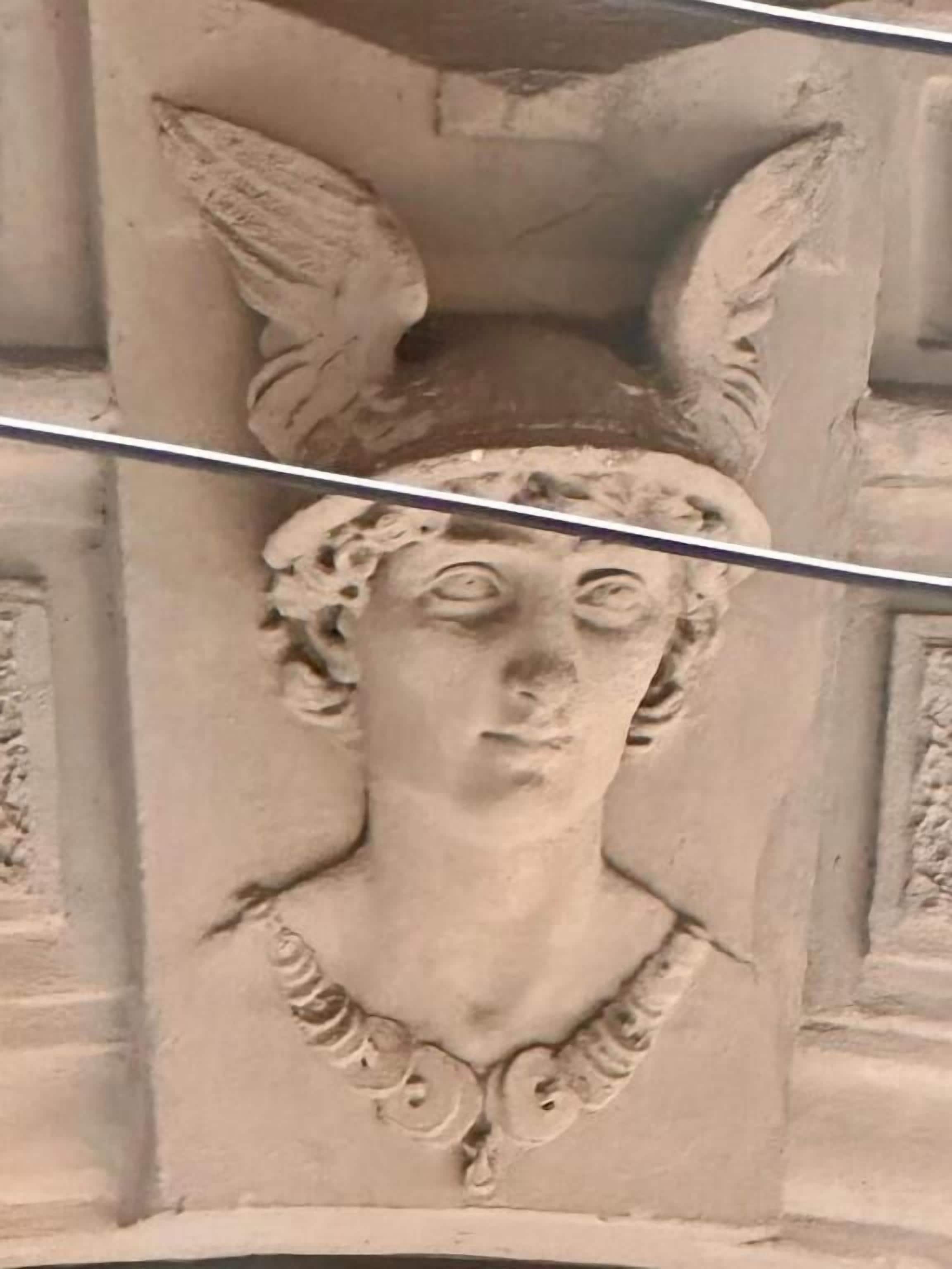 A stone carving of a figure with wings and a necklace.
