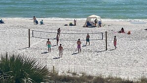 Una cancha de voleibol de playa con jugadores y espectadores.