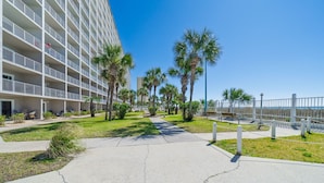 Un hotel con varios pisos, asientos al aire libre y palmeras.