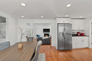 Eine moderne Küche mit weißen Schränken, einem Edelstahlkühlschrank und einem Essbereich mit Holztisch und Stühlen.