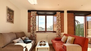 Una sala de estar con dos sofás, una mesa de centro y un ventanal con cortinas.