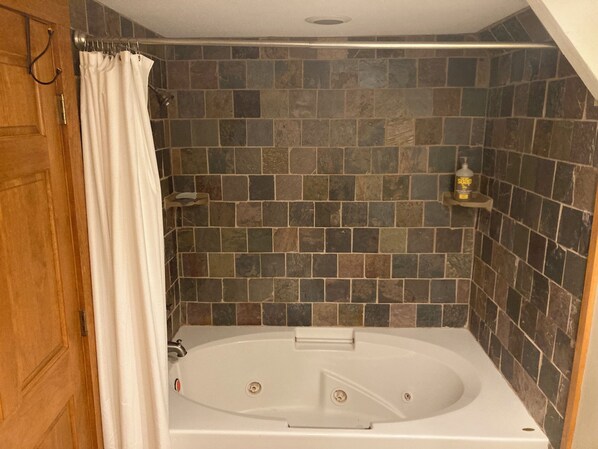 A bathroom with a bathtub, shower curtain, and tiled walls.