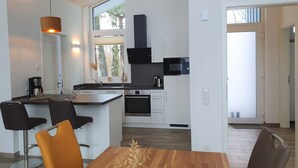 Een moderne keuken met een inbouwoven, magnetron en een groot raam.