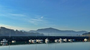 A marina with boats docked, calm water, and a hilly landscape in the background. - Cozy Tourist Apartment in Somo, Ideal for Families. (Somo)