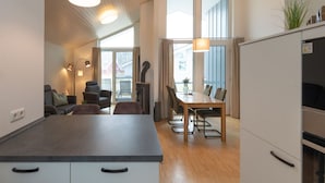 A modern kitchen with a central island, dining area, and large windows. - Ferienhaus mit Sauna im Ferienpark Mirow (Mirow)