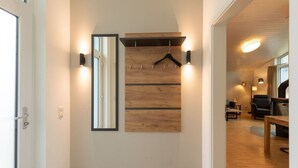 A hallway with a wooden wall panel, a mirror, and wall-mounted lights. - Ferienhaus mit Sauna im Ferienpark Mirow (Mirow)