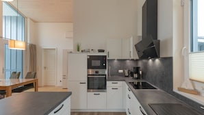 A modern kitchen with white cabinets, a black countertop, and a built-in oven. - Ferienhaus mit Sauna im Ferienpark Mirow (Mirow)