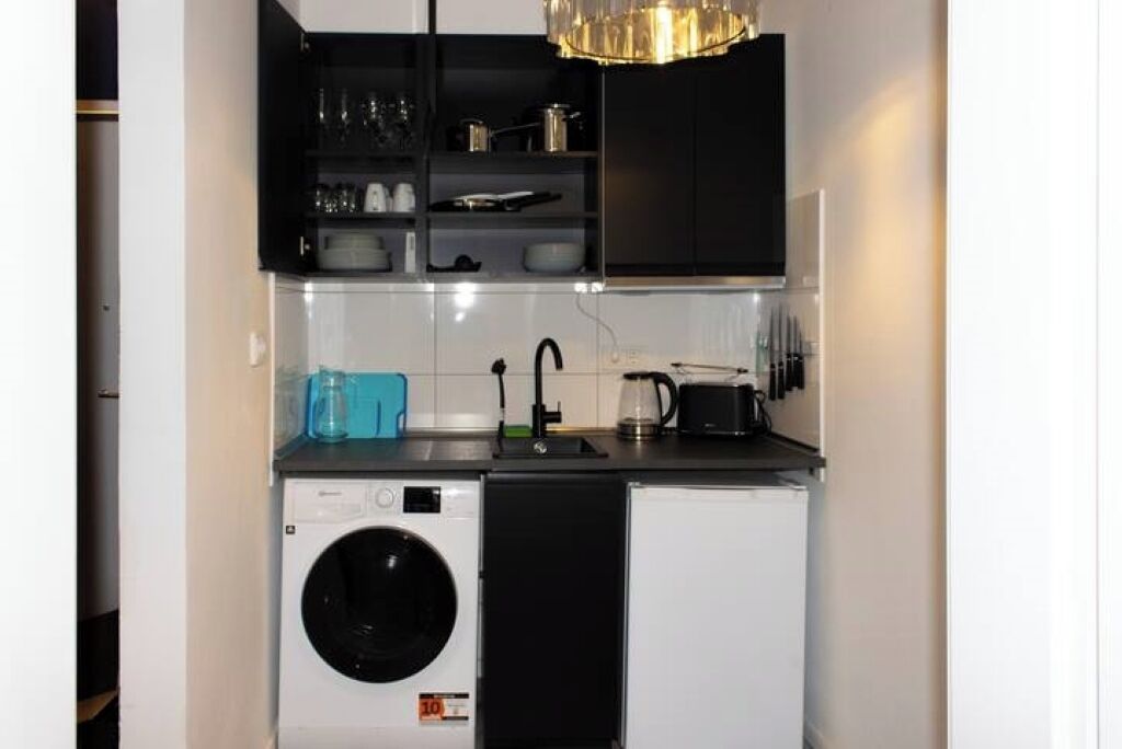 A compact kitchen with a washing machine, a coffee maker, and a sink.