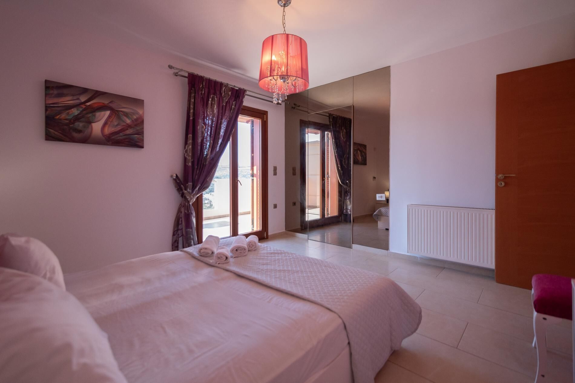 Une chambre à coucher avec un lit, un grand miroir et une vue sur l’extérieur.