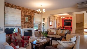 Una sala de estar acogedora con chimenea de piedra, un conjunto de sofás, una mesa de centro y un televisor en una habitación con paredes rojas.