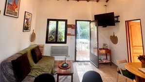 Ein gemütliches Wohnzimmer mit Holzbalkendecke, einer Couch, einem Couchtisch und einem Fernseher.