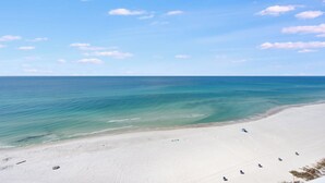 A beach with clear turquoise water, white sand, and a few umbrellas. - Direct Beachfront, wrap balcony, sleeps 10! Shores of Panama (Panama City Beach)