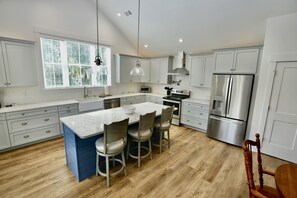 A modern kitchen with a large island, stainless steel appliances, and light gray cabinetry.